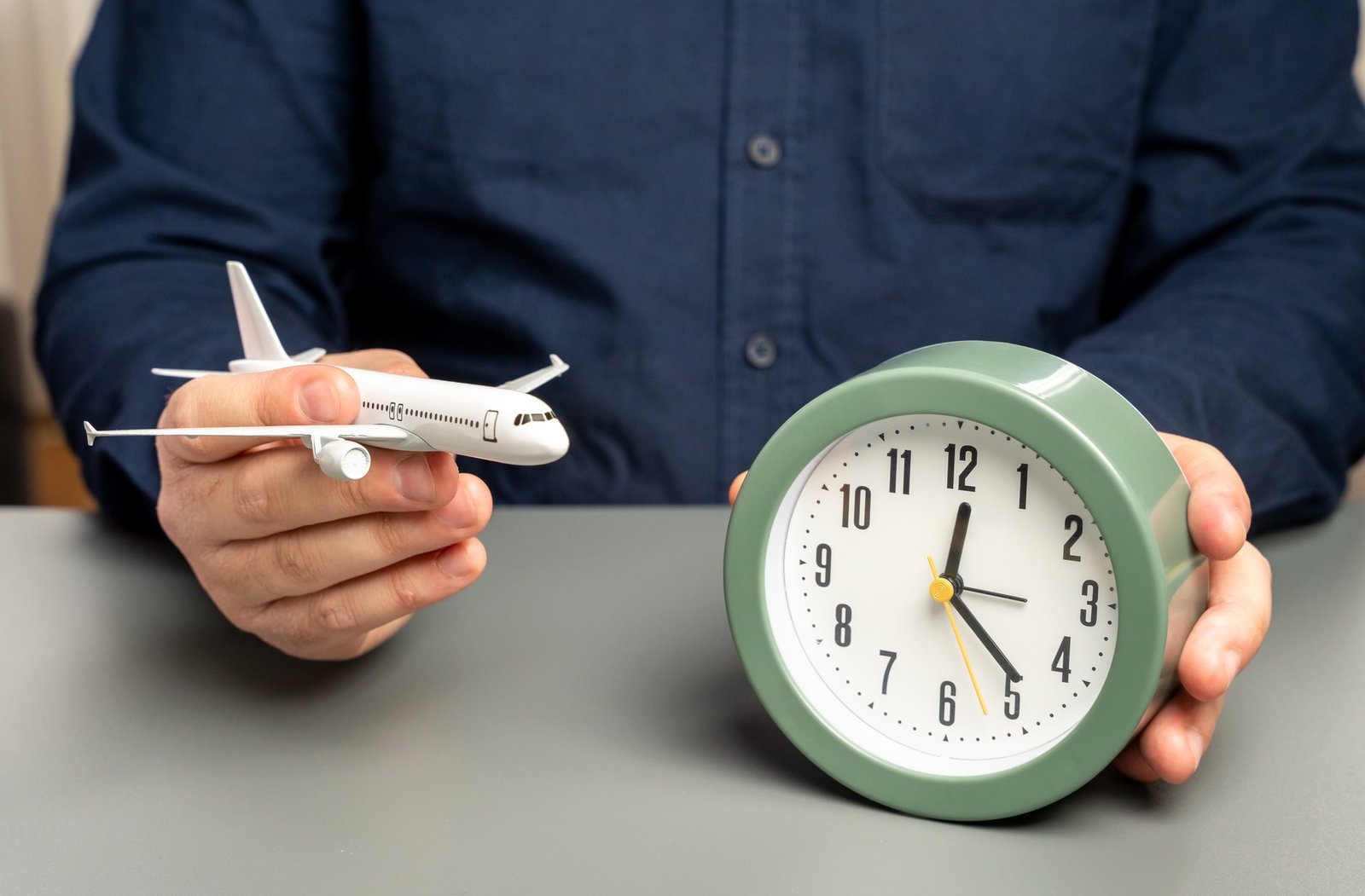 A man holds a passenger plane and a clock. Flight time. Planning a route with transfers. A man holds a passenger plane and a clock. Flight time. Planning a route with transfers.
