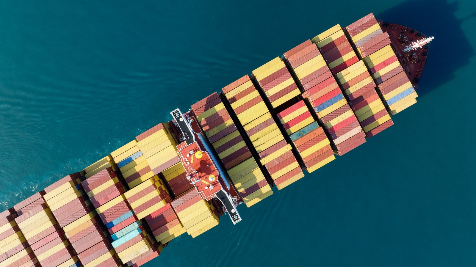 Aerial top view of cargo ship carrying container and running for export goods from cargo yard Aerial top view of cargo ship carrying container and running for export goods from cargo yard