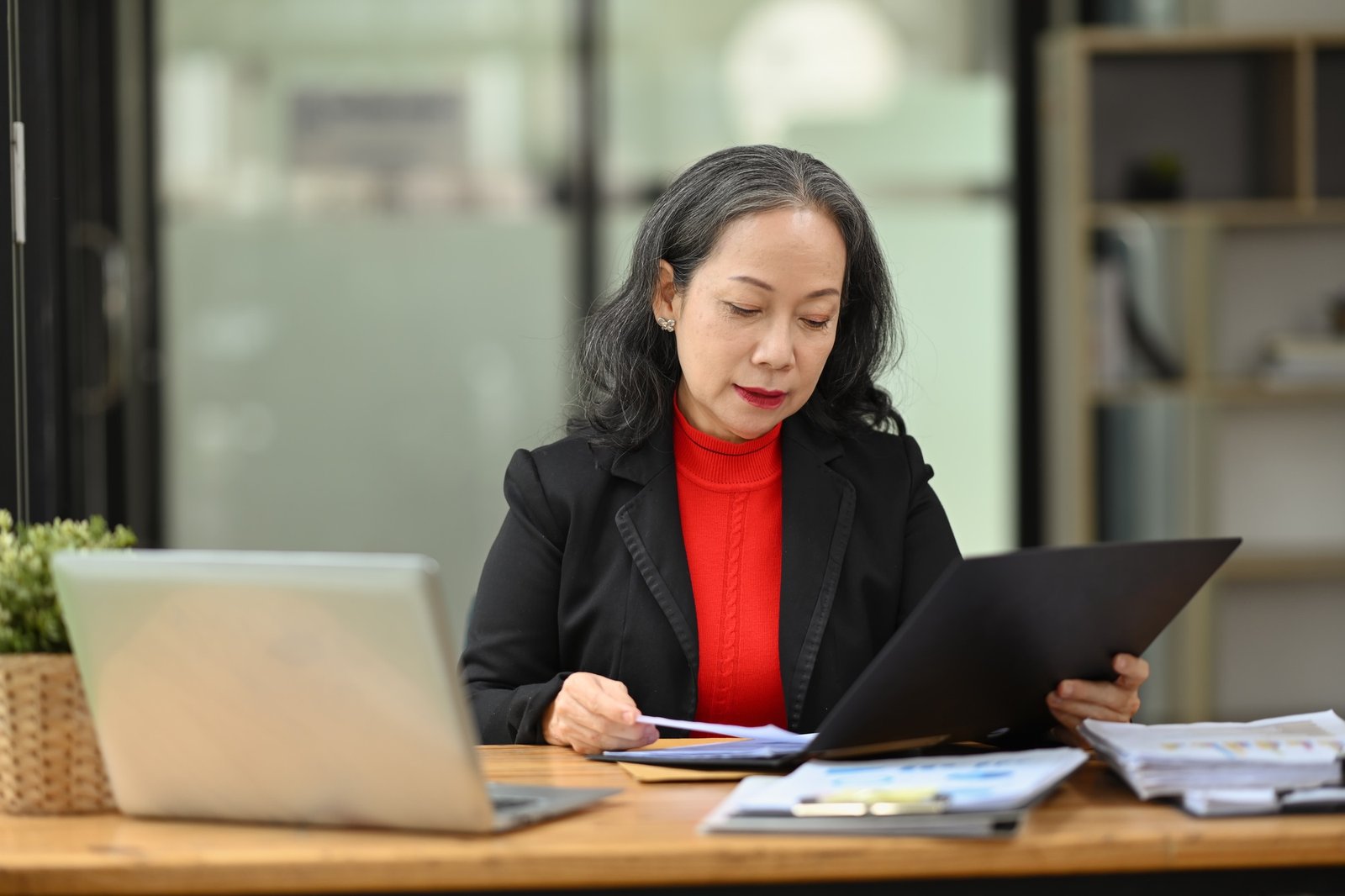 Professional senior woman accounting manager checking financial documents at workplace