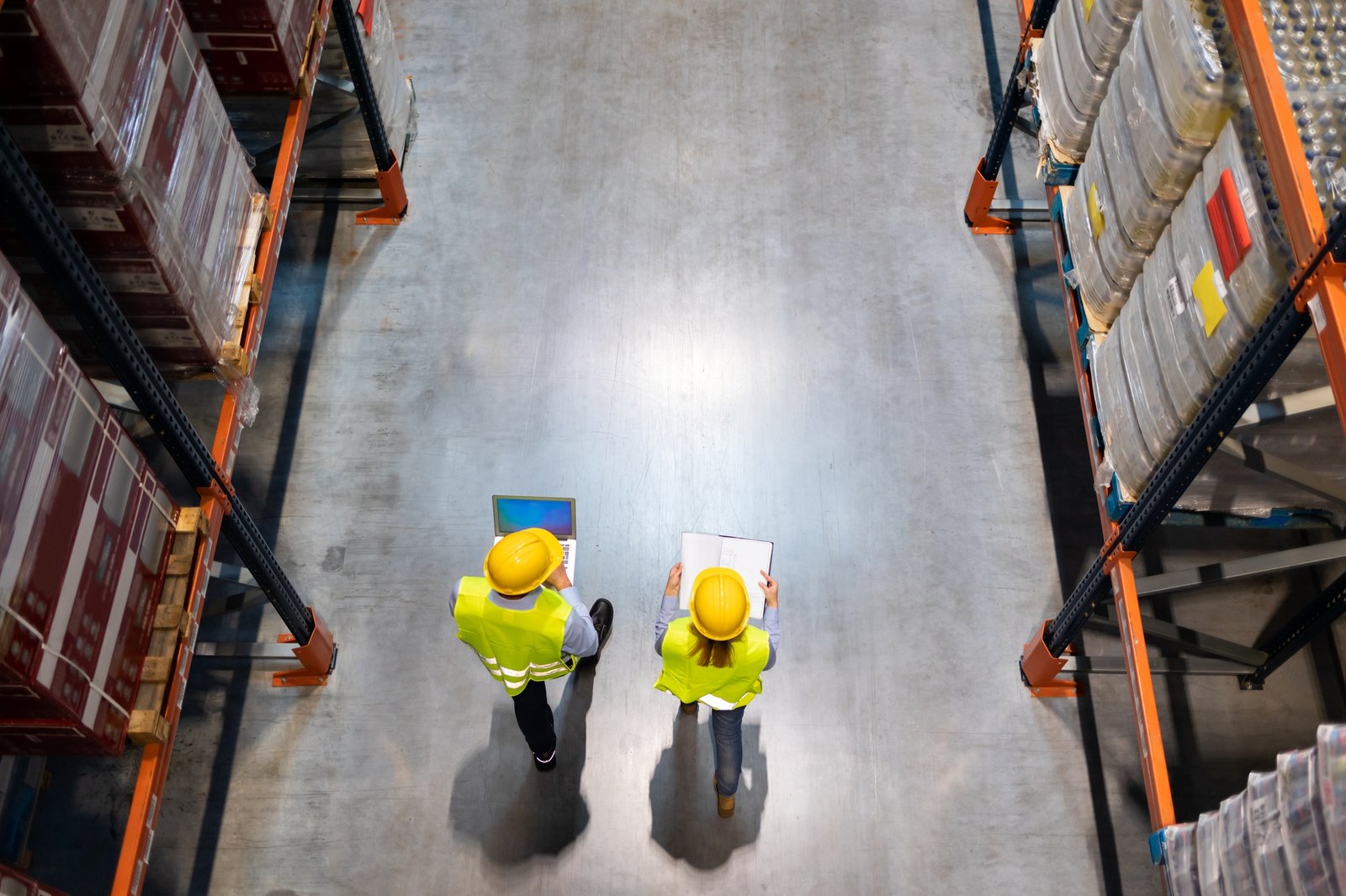 Warehouse workers consult delivery plans using laptop and electronic database Warehouse workers consult delivery plans using laptop and electronic database