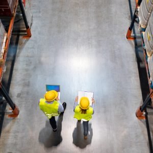 Warehouse workers consult delivery plans using laptop and electronic database